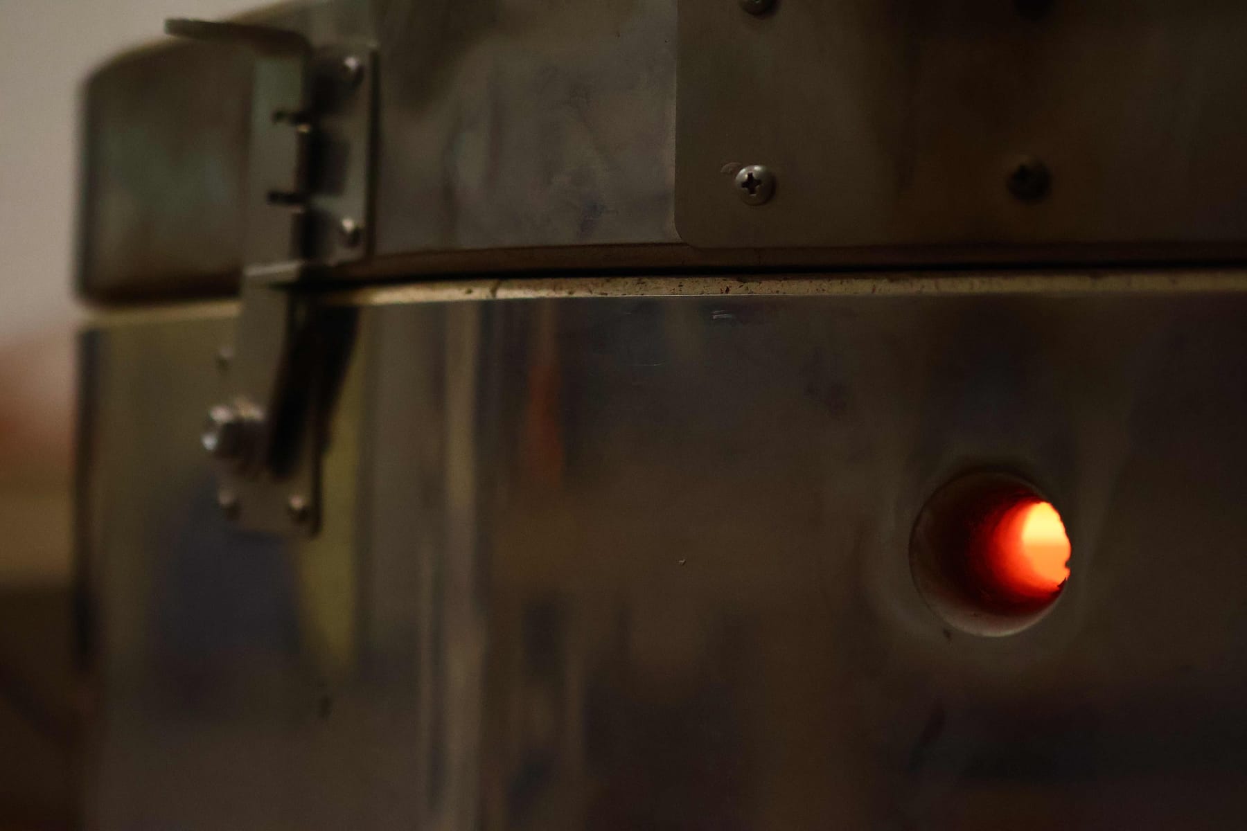 The studio kiln firing, glowing orange through the spy-hole