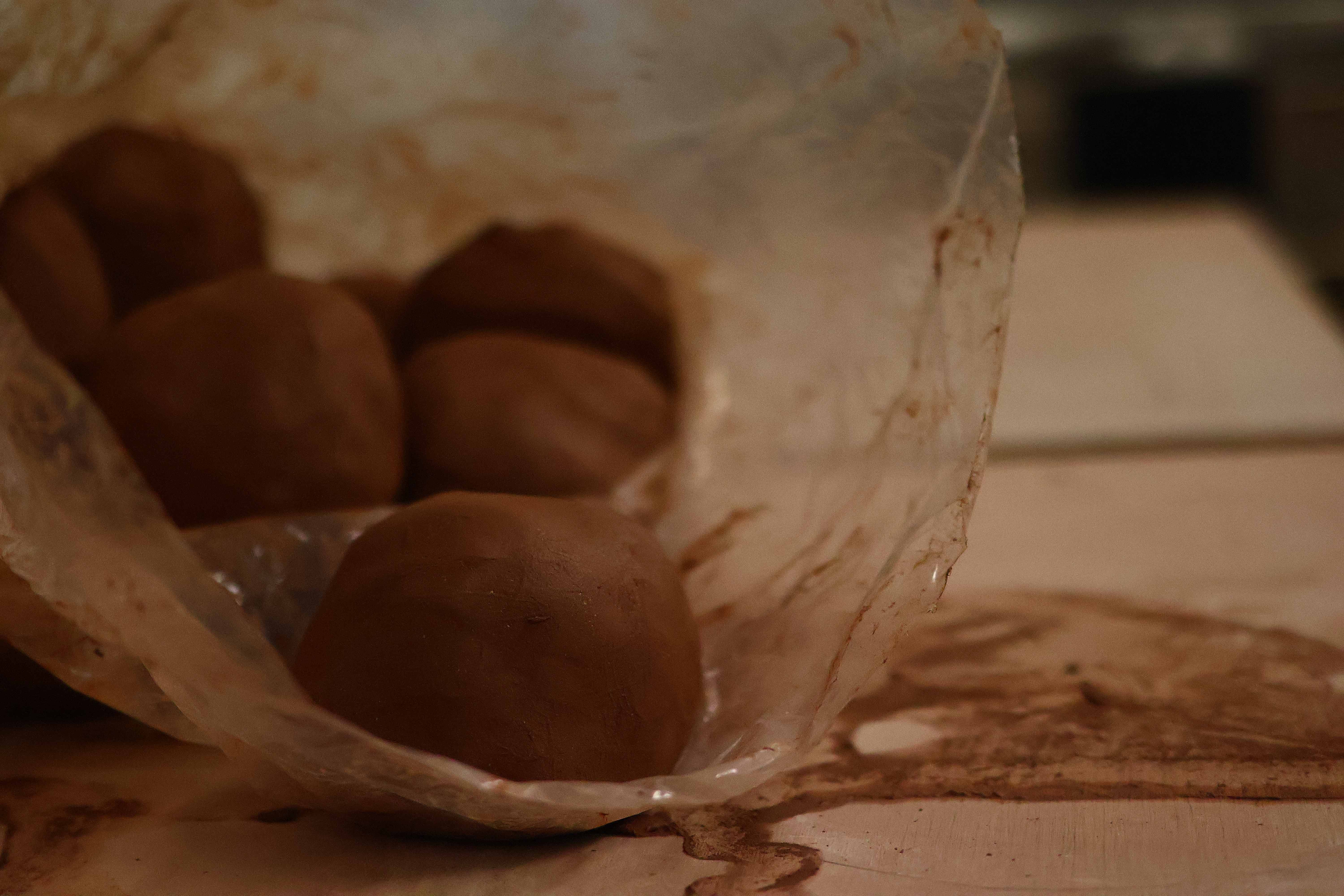 Wedged balls of raw terracotta clay resting in a studio bag on the worktable