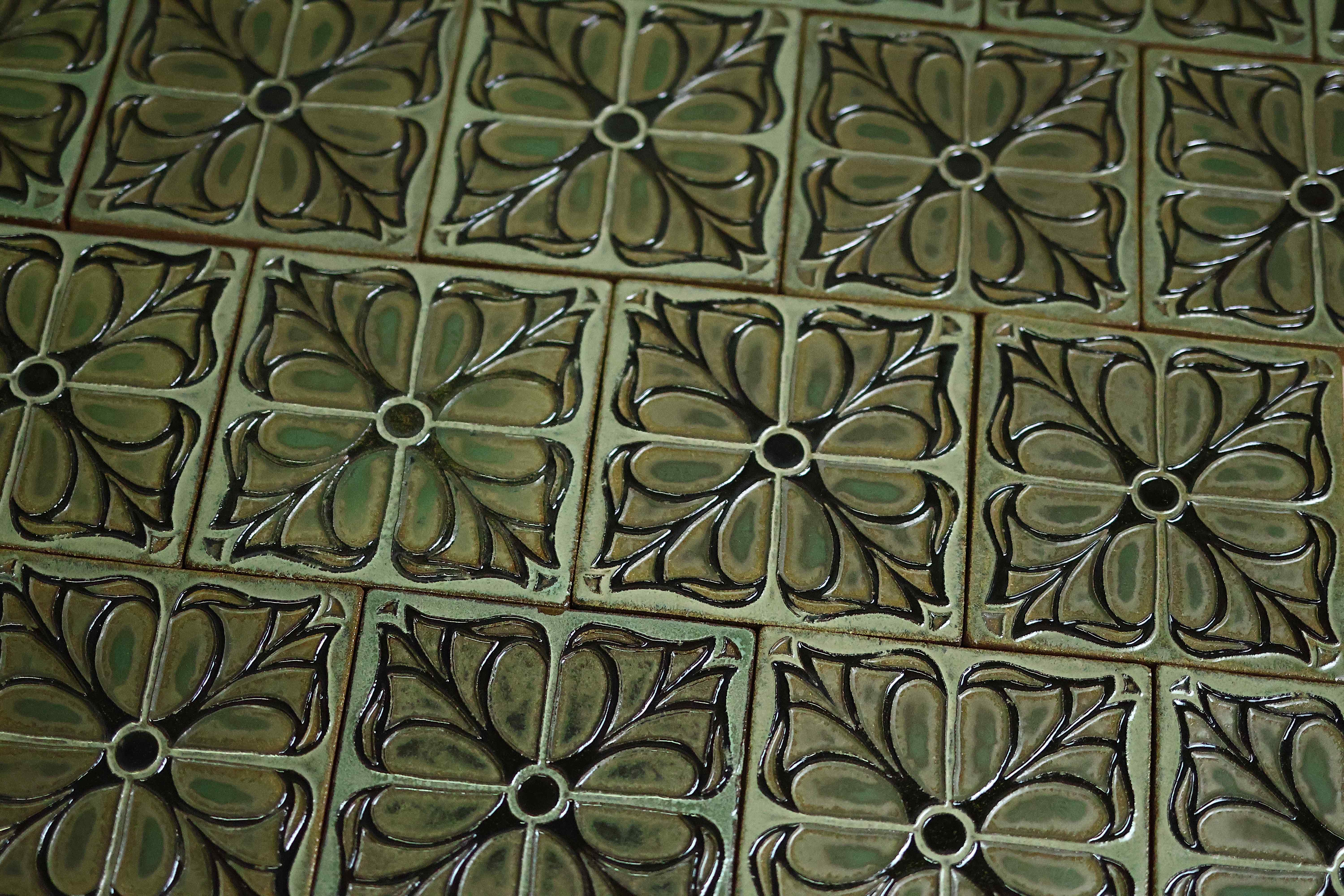 Mossy green Cuenca tiles with a raised four-petal floral relief, arranged in a grid
